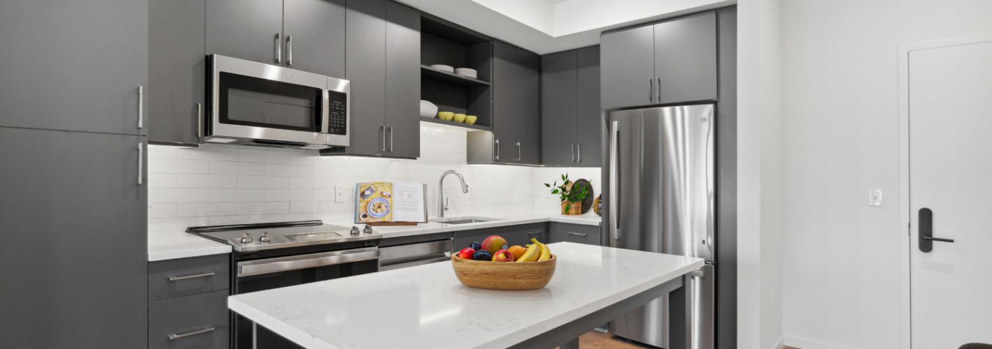 Broad & Washington : Immerse yourself in a kitchen outfitted with stainless steel appliances and a classic tile backsplash. 	